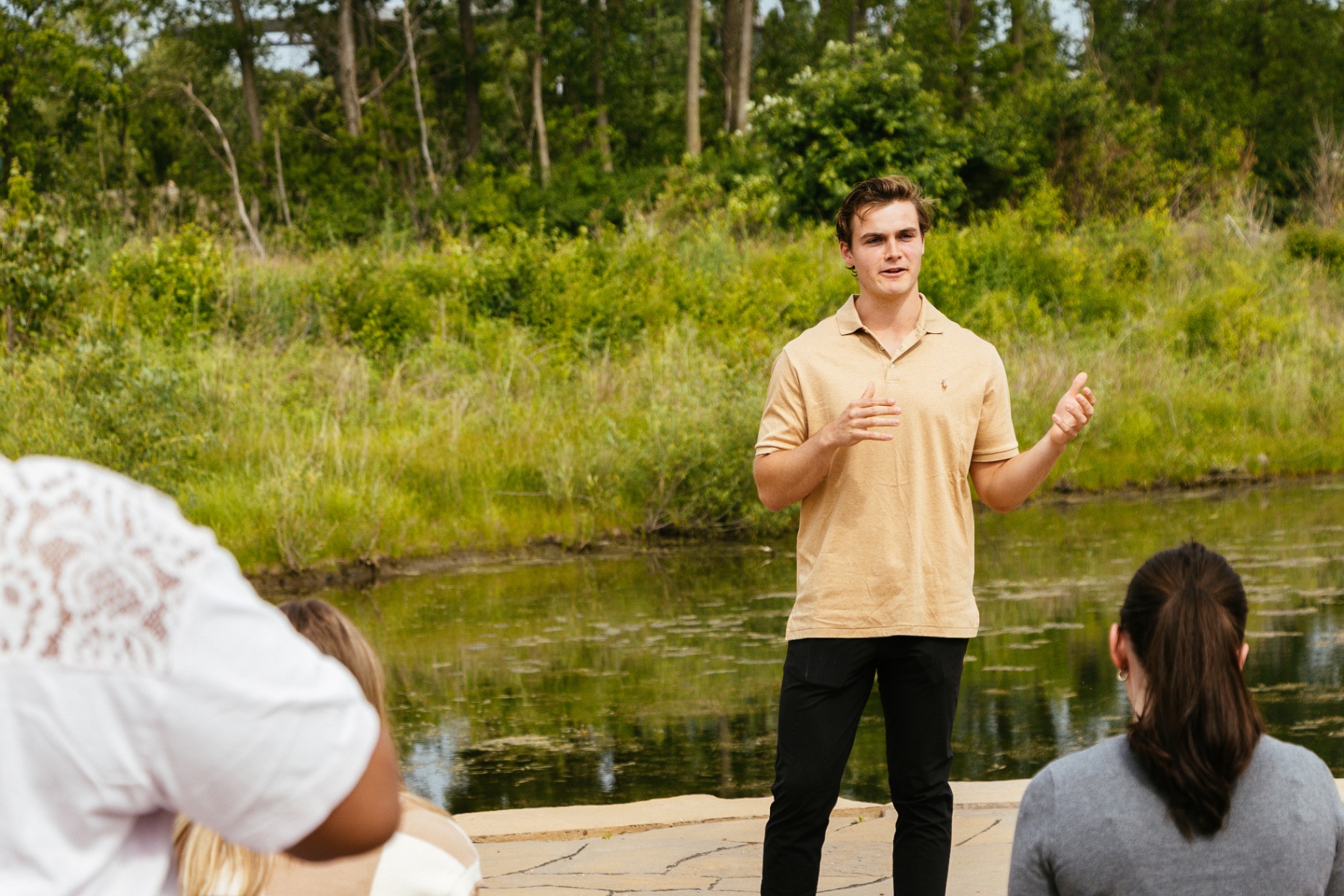 Hunter Smith speaking to a small group by a pond
