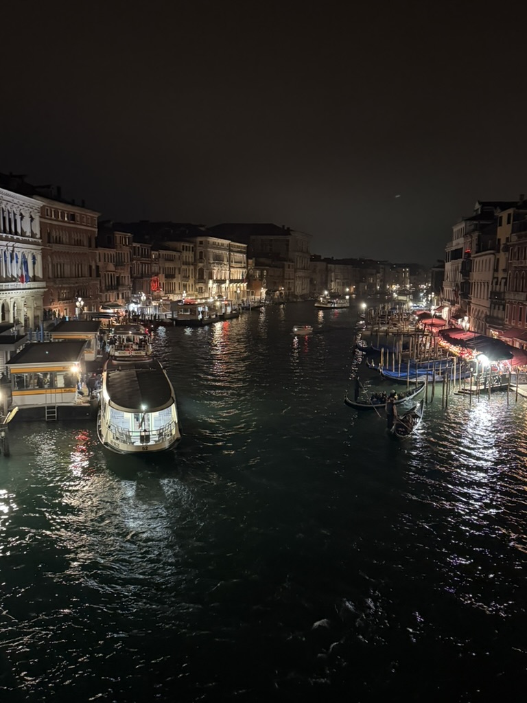 Venice Grand Canal at night, lit boats and palazzos reflected on the water