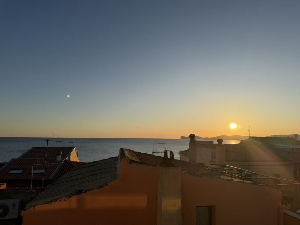 Sunset over the rooftops and sea, golden light spilling across the horizon